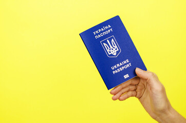 Ukrainian passport in hand on a yellow background