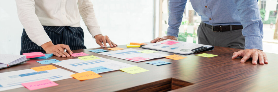 Creative Group Of Business People Brainstorming Use Sticky Notes Picking To Share Idea On Table Decision Choosing Concept For Developing Plan In Business Conference Room.