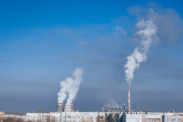 combined heat and power (CHP) system with industrial chimneys and white smoke on bright blue sky background