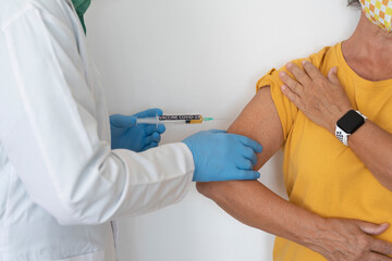 Coronavirus. The hands of a doctor injecting the covid-19 coronavirus vaccine to a woman in a yellow shirt