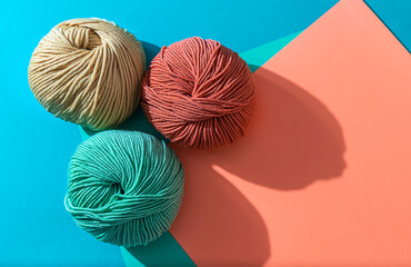 Woolen yarn of different colors on a colored background. Hand knitting.