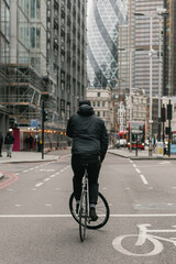 Fixed gear cyclist track stands in London city landscape