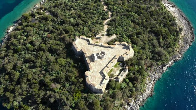 Historic fortress of Medieval era in Albania built on rocky island surrounded by blue turquoise sea