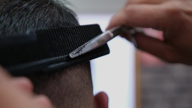 Extreme close-up as a barber finishes up blending a fade on a male customer's haircut.