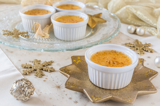 Creme brulee - traditional french vanilla cream dessert with caramelised sugar on top, served on a gold star-shaped plate with gold and white christmas decoration