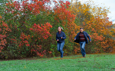 couple running in autumn city park, happy people together, beautiful nature with colorful leaves