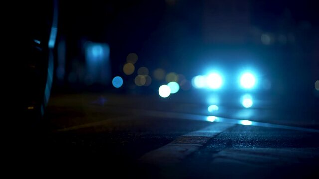 Night time road traffic in the city. Car headlights illuminate the streets in Munich. Selective focus on the road with blurred background traffic