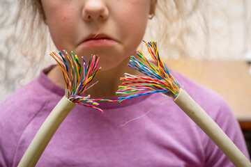 Breakage of colored wires. Little girl tears the communication internet cable with her hands....