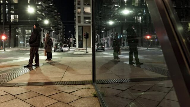 People And Vehicles On Bustling Street At Night - Reflection On Glass Wall Of A Building At Barcode District In Oslo - timelapse, zoom-in