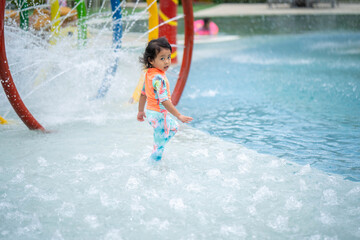 Little girl in swimming suit playing at waterpark.