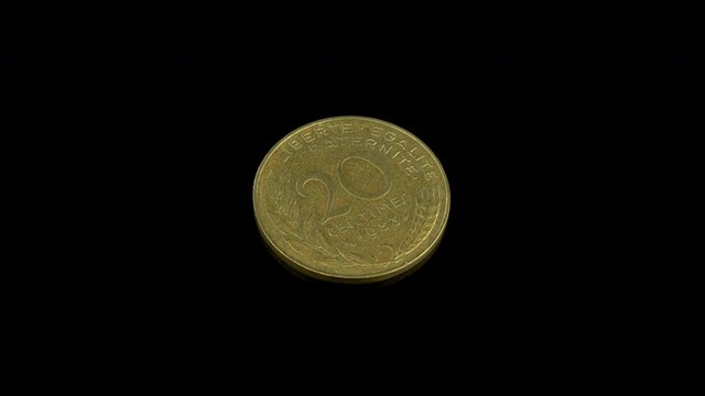 French 20 centimes coin from 1983 rotating on a black background