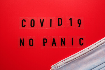 Words covid 19 no panic on a red background and a medical mask.