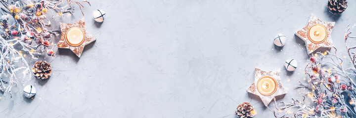 A composition of candlesticks, snow branches and Christmas decorations on gray background.