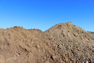 Close-up of a large pile of earth against the blue sky.