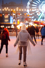 Young  woman ice skating on the ice arena in the city square in winter on Christmas Eve. Winter holiday. New Year magic. Lights around.
