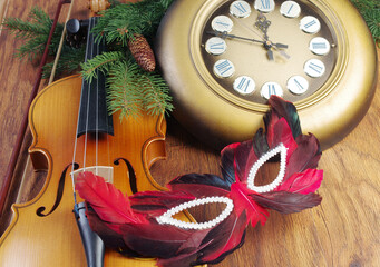 Violin, masquerade mask, wall clock and tree branch with Christmas decorations.