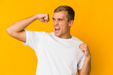 Young caucasian handsome man raising fist after a victory, winner concept.