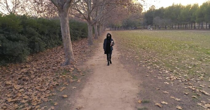 mujer de negro pasea hacia delante con libro en la mano en bosque de oto&ntilde;o