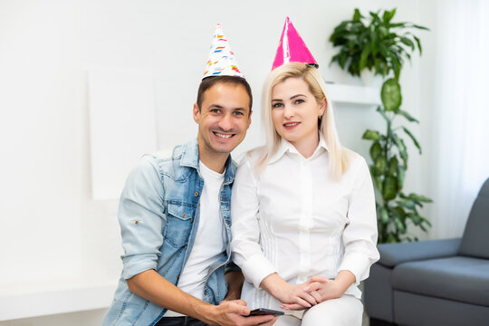 Young couple or friends in party hats having fun virtual celebration via video call.