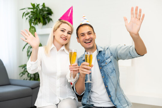 Young couple or friends in party hats having fun virtual celebration via video call.