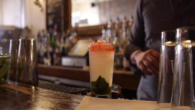 Bartender Adds Syrup, Mint, Straws to Queen's Park Swizzle, Mojito Cocktail on Bar