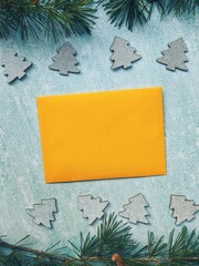 Christmas or New Year composition. Paper yellow envelope with a spruce branches, decorations on a blue background. Flat lay style. New Year greeting card. 