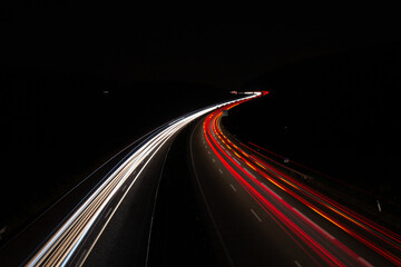 Fototapeta na wymiar Cars light trails on a curved highway at night. Night traffic trails
