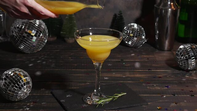 Pouring orange juce into a glass of champagne. New Year or Birthday party with a mimosa coctail and mirror disco balls
