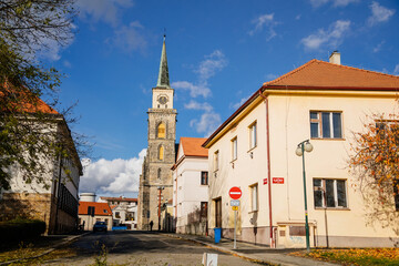 Fototapeta na wymiar Medieval catholic old church of Saint Jilji with gothic high clock tower in sunny autumn day, street view, Nymburk, Central Bohemia, Czech Republic