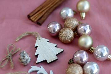 Various Christmas decorations and cinnamon sticks on pink background. Selective focus.