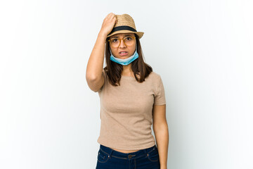 Young latin woman wearing hat and mask to protect from covid isolated on white background being shocked, she has remembered important meeting.