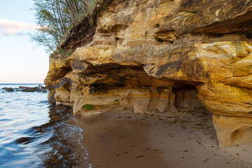 Sandstone cliff with caves on the shore of Baltic sea. Sunset time. Estonia.