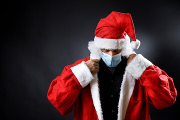 Babbo natale con mascherina chirurgica si sistema il colletto  , isolato su sfondo nero