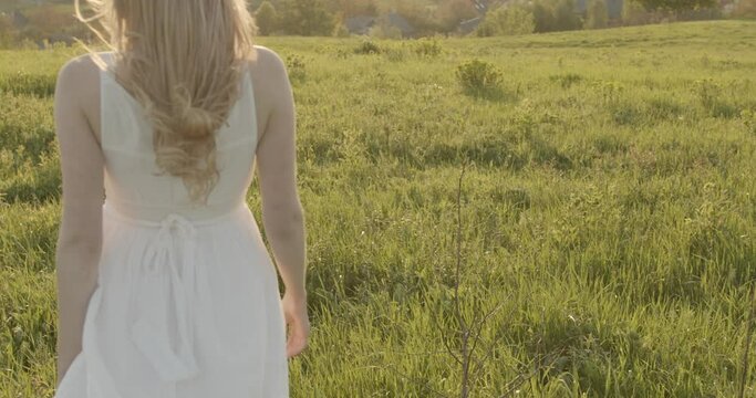 seductive woman in a white dress walks on the meadow