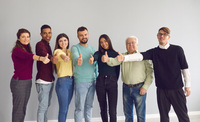 Group of happy diverse people standing together, giving thumbs-up and looking at camera