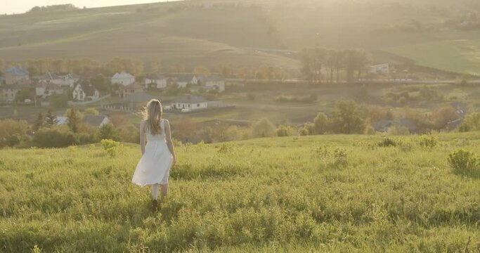 girl walking on the grass in a white dress enjoying the scenery