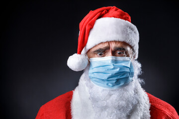 Babbo natale con mascherina chirurgica guarda terrorizzato verso il basso,, isolato su sfondo nero