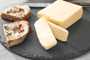 Fresh butter and slices of bread on dark board