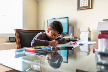 Obraz premium Concentrated child doing homework in daddy's office