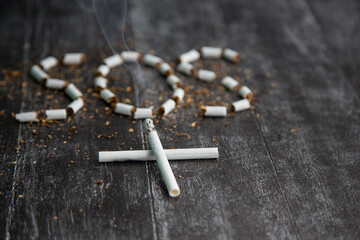 the ash and cigarette look like a cross, an artistic concept for world no tobacco day. Sign SOS of tobacco. Health risks of nicotine. The cigarette kills