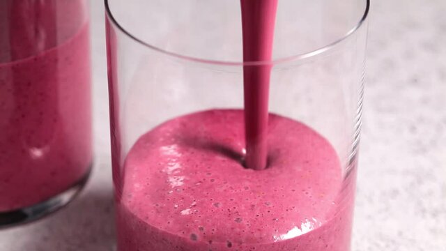 Cooking berry smoothie with nuts, light gray background. Healthy detox drink concept.