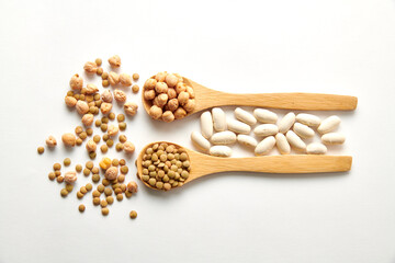 A pile of chickpeas on a wooden spoon and scattered on the white surface