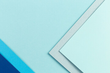 Material design blue background. Craft paper sheets are folded in different ways. A photo.