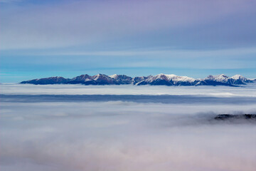 Sun is shining at foggy autumn day on top of the low Tatry looking into mountain tops of the high Tatry in distance