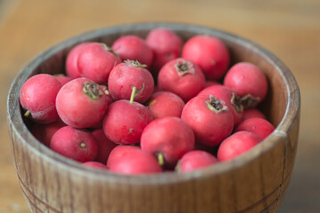 Top view of red Scarlet Hawthorn fruits (Crataegus coccinea), piled up in wooden bowl