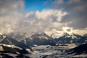 Wolkenstimmung im Winter über den Alpen mit blauem Himmel