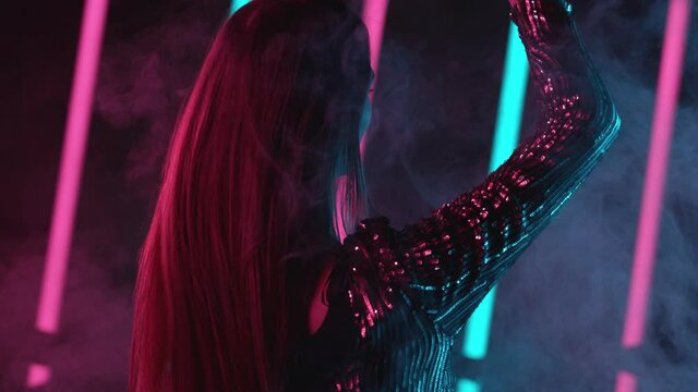 Slow motion of young woman dancing with neon lights background, backside. Filmed on high speed cinema camera.