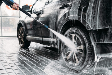 Woman washing his car in a self-service car wash station.Car wash self-service. 