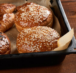 baked sesame buns on brown parchment paper, ingredient for a hamburger