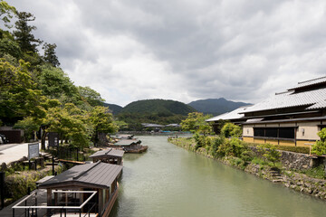 river lake view in kyoto japan, with boats in the green water, cloudy sky, and greenery